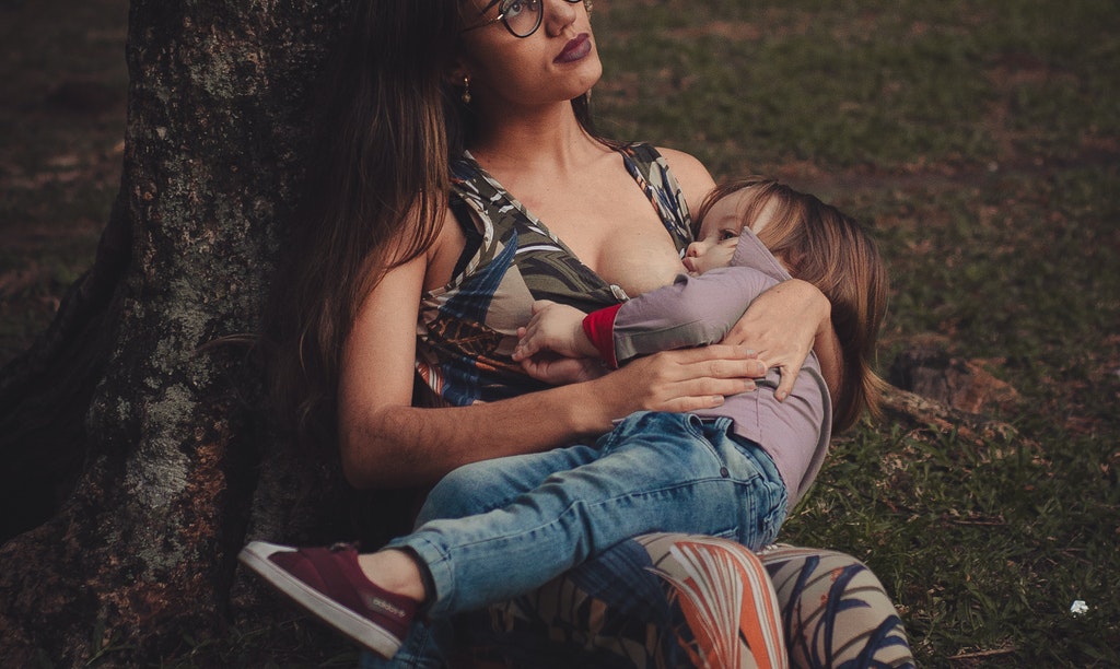 kobieta karmiąca dziecko w parku